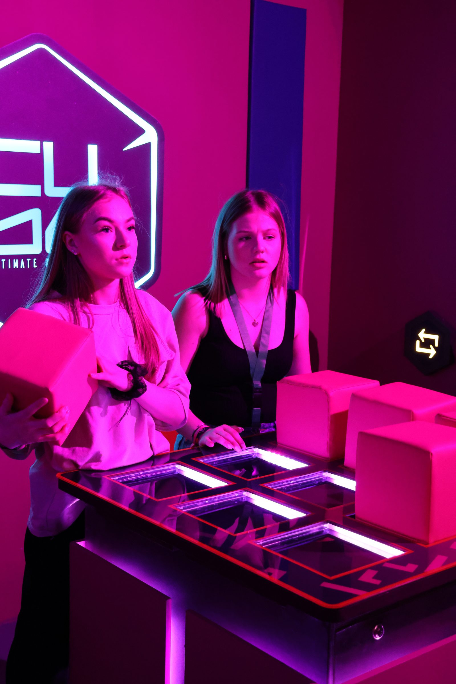 Deux joueuses devant un mur de défis lumineux du Cube Challenge chez Team Square